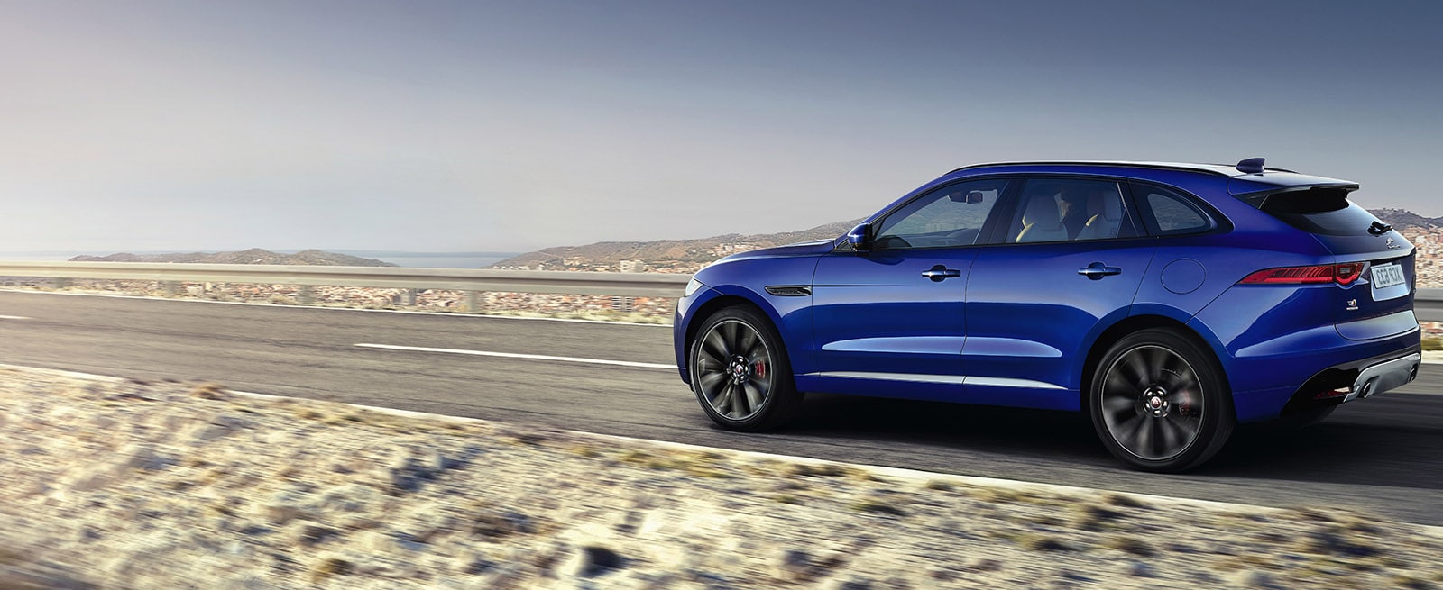 Blue Jaguar F-Pace Driving Along A Desert Road