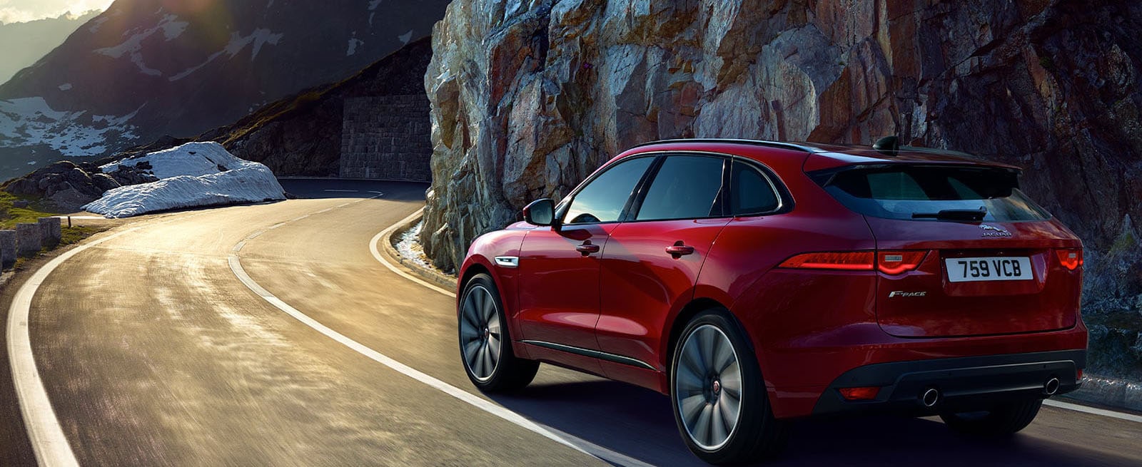 Red F-Pace Driving Along a Mountainous Road